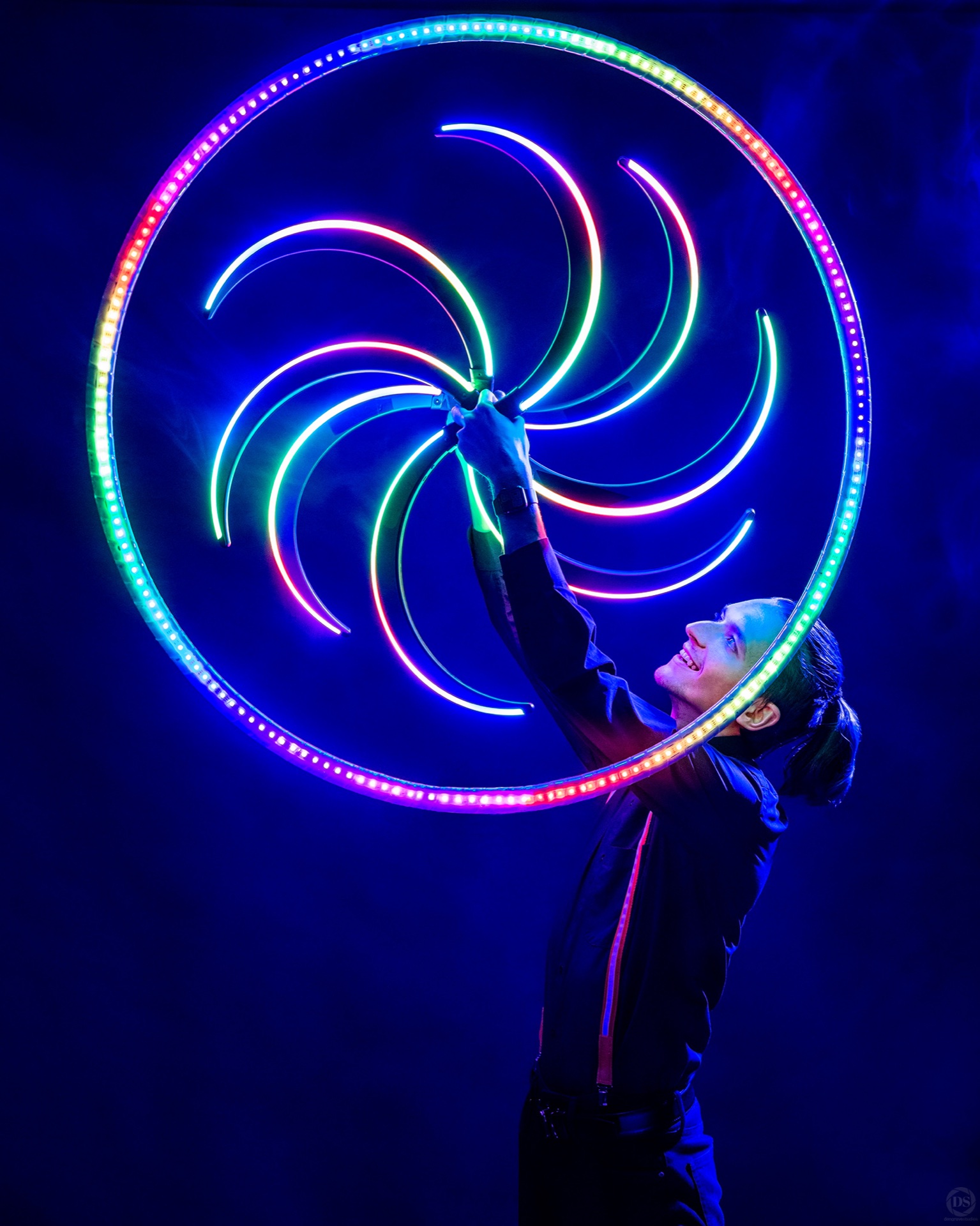 Performer holding illuminated rings in a spiral pattern under blue lighting